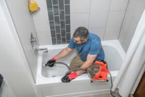 A plumber using specialized tools to clean drains.
